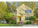 Inviting yellow two-story home featuring a landscaped front yard, trimmed bushes and a picket fence at 6005 Lanai Ln, Tega Cay, SC 29708