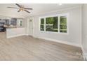 Bright living room with wood-look floors, large window, ceiling fan, and seamless transition to the kitchen at 706 Lowell Ave, Lowell, NC 28098