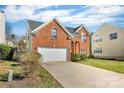 Two-story red brick home with a two-car garage and well-kept lawn with partial driveway view at 98 Poplar Woods Dr, Concord, NC 28027
