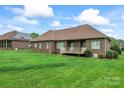 A spacious backyard with green lawn surrounds a brick home, featuring a cozy back deck at 132 Postell Dr, Statesville, NC 28625