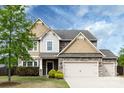 Charming home with stone and siding exterior, two-car garage, and mature landscaping at 15225 Kissimmee Ln, Mint Hill, NC 28227