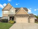 Two-story home featuring a two-car garage, stone accents, and a well-manicured lawn at 15225 Kissimmee Ln, Mint Hill, NC 28227