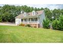 This home is surrounded by lush green trees, a charming front porch, and mature landscaping at 1812 Sam Smith Rd, Fort Mill, SC 29708