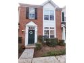 Inviting brick townhouse with a green front door, decorative wreath, and manicured shrubs at 19057 Coachmans Trce, Cornelius, NC 28031