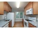 A well-lit kitchen featuring hardwood floors, granite countertops, and white appliances at 676 Forest Nw St, Concord, NC 28025