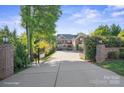 Stately home featuring a gated entrance and long driveway, surrounded by mature trees at 7944 Park Rd, Charlotte, NC 28210