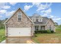 Charming home featuring a stone and vinyl exterior, attached two-car garage, and well-maintained landscaping at 2408 Joes Lake Rd, Shelby, NC 28152