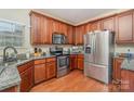 Modern kitchen featuring stainless steel appliances, granite countertops, wood cabinetry, and natural lighting at 2408 Joes Lake Rd, Shelby, NC 28152
