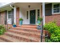 Inviting front entry with brick steps, decorative planters, and charming green door with wreath at 2515 Sheffield Dr, Gastonia, NC 28054