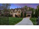 Elegant home featuring a long driveway, iron gate, and lush landscaping at 4400 Sharon View Rd, Charlotte, NC 28226