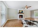 Bright living room featuring a white-painted fireplace with a rustic wood mantel, wood floors, and a ceiling fan at 11700 Fernhurst Ln, Charlotte, NC 28277