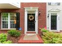 Up close view of townhome entryway with black front door, wreath, and security system sign at 12905 Bullock Greenway Blvd, Charlotte, NC 28277