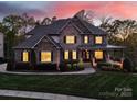 Stunning exterior of a two-story home at dusk, showcasing its brick facade, illuminated windows, and welcoming front porch at 141 Forsythia Ln, Tega Cay, SC 29708