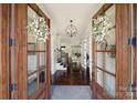 Inviting home entryway with dark wood floors, elegant chandelier, and a view into the living room and staircase at 141 Forsythia Ln, Tega Cay, SC 29708