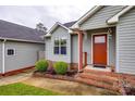Inviting front entrance with brick steps, red door, manicured landscaping, and light green siding at 1545 Wimbleton Woods Dr, Fort Mill, SC 29708