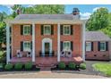Charming brick home featuring a covered front porch, black shutters, and classic architectural details at 203 Mt Holly Huntersville Rd, Huntersville, NC 28078