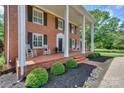 Inviting covered porch with rocking chairs and beautiful landscaping, perfect for relaxing at 203 Mt Holly Huntersville Rd, Huntersville, NC 28078