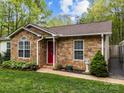 Close-up of a single-story home with a stone facade, manicured landscaping, and a bright red front door at 214 Creek View Rd, Mooresville, NC 28117