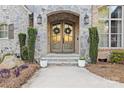 Close-up of double front doors framed by stone, sconces, and manicured greenery at 4025 Foxes Trl, Cramerton, NC 28032