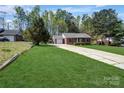 A brick home with a well-kept lawn and a long driveway leading to a one-car garage on a sunny day at 6549 Wesbrook Dr, Charlotte, NC 28214