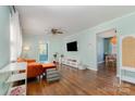 Bright living room with hardwood floors, large windows, a television, and a view into the dining area at 665 Melbourne Ct, Charlotte, NC 28209