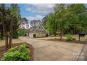 Long driveway leads to a brick house with a three-car garage surrounded by trees at 7982 Buena Vista Dr, Denver, NC 28037