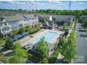 Aerial view showcasing a community pool with lounge chairs and multiple townhome buildings at 9914 Ainslie Downs St, Charlotte, NC 28273