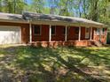 Charming brick ranch with a covered front porch and a well-manicured lawn at 1199 Riding Trail Ln, Concord, NC 28027
