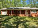 Charming brick ranch with a covered front porch and a well-manicured lawn at 1199 Riding Trail Ln, Concord, NC 28027
