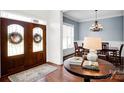 Inviting foyer features a wooden door, a round foyer table and hardwood floors that lead into the dining room at 12932 Westmoreland Farm Rd, Davidson, NC 28036