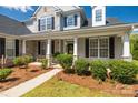 Inviting front porch with stone accents, white columns, seating area and lush landscaping creating an appealing entry at 2004 Ptarmigan Ct, Waxhaw, NC 28173