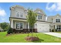 Charming two-story home featuring a gray exterior, manicured lawn, and a two-car garage at 2017 Embassy Ct # 51, Charlotte, NC 28213