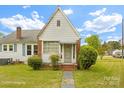 Quaint single-story home with brick accents, awning, and classic shutters surrounded by mature landscaping at 203 Ackert Ave, Salisbury, NC 28144