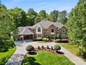Stately brick home boasts lush landscaping, circular drive, and attached garage with a basketball hoop at 5001 Oxfordshire Rd, Waxhaw, NC 28173