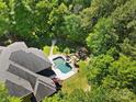 Aerial view showcasing a sparkling in-ground pool with spa, waterfall feature, and mature trees at 5001 Oxfordshire Rd, Waxhaw, NC 28173
