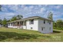 View of a white single story home with a cozy front porch and a lush green yard at 6599 Mcintosh Rd, Stanley, NC 28164