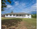 Inviting single story home featuring a white painted brick exterior, dark shutters, and a cozy front porch at 6599 Mcintosh Rd, Stanley, NC 28164