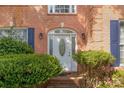 Elegant front door with decorative glass and sidelights, framed by lush greenery and brick steps, and decorative sconces at 6615 Wickville Dr, Charlotte, NC 28215