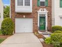 Welcoming brick townhome exterior featuring green door, shutters, and one-car garage at 10308 Garrett Grigg Rd, Charlotte, NC 28262