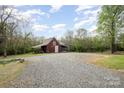 View of a rustic barn with a gravel driveway, set in a scenic countryside environment at 1151 Trull Hinson Rd, Wingate, NC 28174