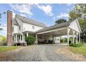 Rear view of white two-story farmhouse with covered parking area and large brick chimney on blue sky day at 1151 Trull Hinson Rd, Wingate, NC 28174