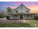 Inviting two-story white farmhouse with a covered porch, offering a warm and welcoming curb appeal at 1151 Trull Hinson Rd, Wingate, NC 28174