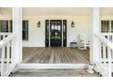 Cozy front porch featuring a black front door, classic rocking chair, and decorative outdoor lanterns at 1151 Trull Hinson Rd, Wingate, NC 28174
