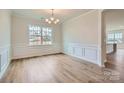 Formal dining area features beautiful wood floors, wainscoting, a modern chandelier, and a large window at 1996 Copper Path Dr, Fort Mill, SC 29715