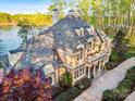 Stunning lakefront property featuring a stone and stucco exterior, multiple windows, and lush greenery at 210 Dexter Ave, Kannapolis, NC 28081