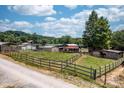 Expansive horse farm with multiple barns, fencing, and lush green pastures under a blue sky at 291 Love Valley Rd, Statesville, NC 28625