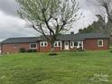 Charming brick home featuring a lush front yard, a mature tree, and a cozy front porch with inviting seating at 5373 Nc Hwy 16 N Hwy, Taylorsville, NC 28681