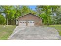 Attached two-car garage with a concrete driveway surrounded by a grassy yard and mature trees at 600 Community Ln, Lancaster, SC 29720