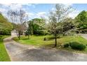 Exterior view of the home showing the driveway, grassy front yard with mature trees and landscaping at 608 Grace St, Shelby, NC 28150