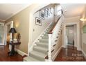 Elegant staircase with carpet runner, white banister, and natural light from a nearby window at 801 Berkeley Ave, Charlotte, NC 28203